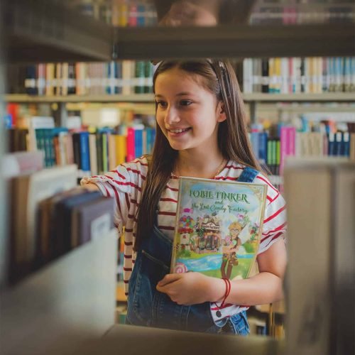 smiling-girl-holding-a-book-template-at-a-library-a19275 (1)